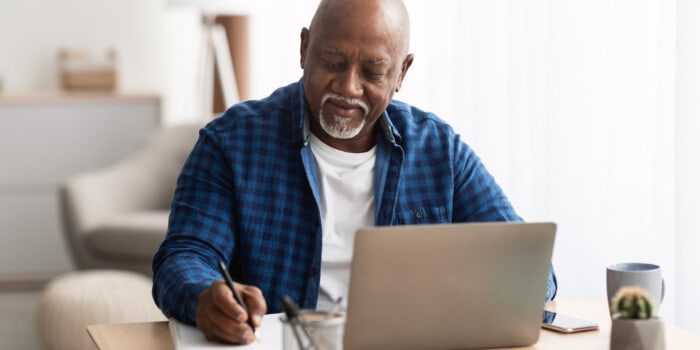 Senior Black man taking notes about the phi test from his computer.