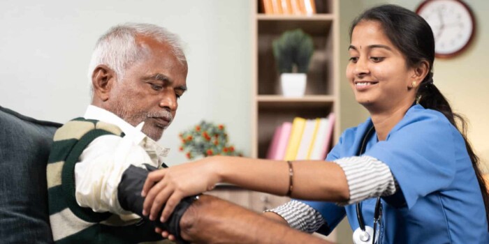 Elder man getting his blood pressure taken by a young nurse.